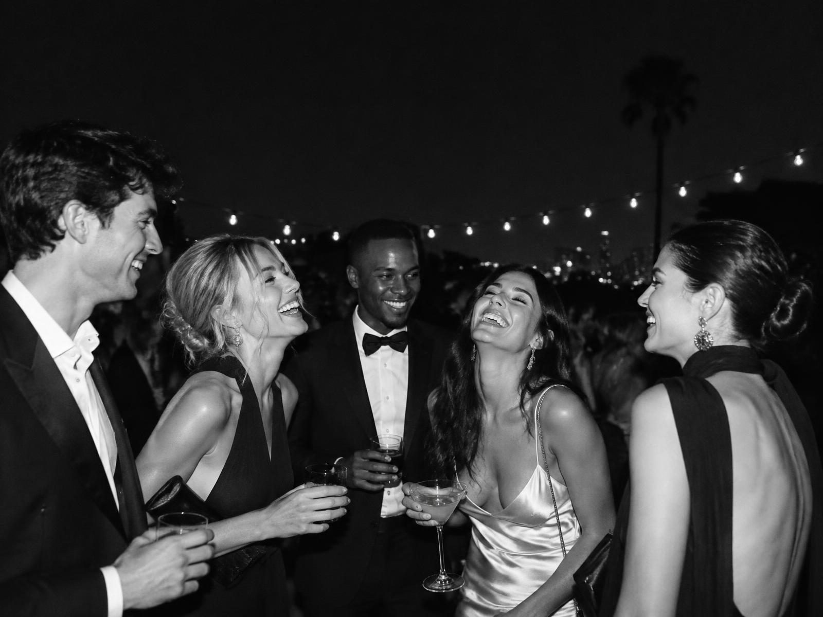 friends laughing together under string lights at an evening event